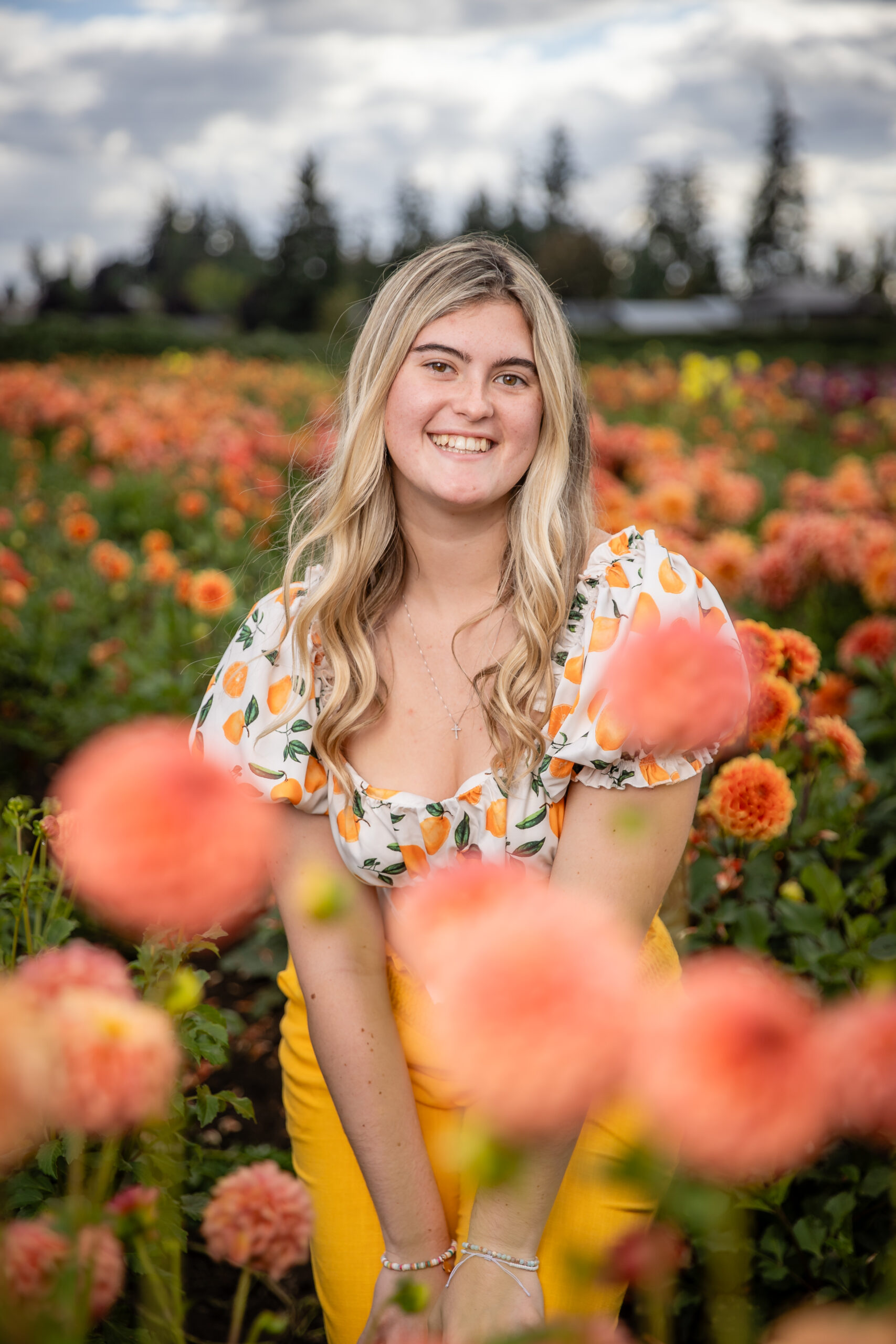A student in a field of orange flowers, smiling at the camera. 