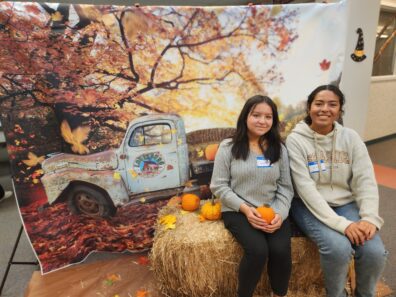Two students posing in front of a fall photo backdrop at the 2022 Fall Social.