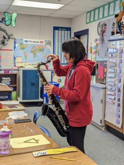 Student prepping saxophone to play Christmas music for elementary students during volunteering