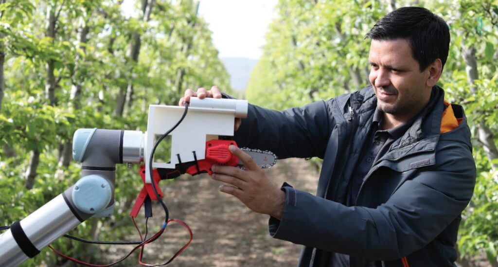 Researcher working on robotic arm in an orchard