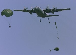 Cadets jumping out of a military aircraft with parachutes.