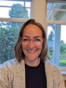 white woman with short brown hair and glasses, smiling