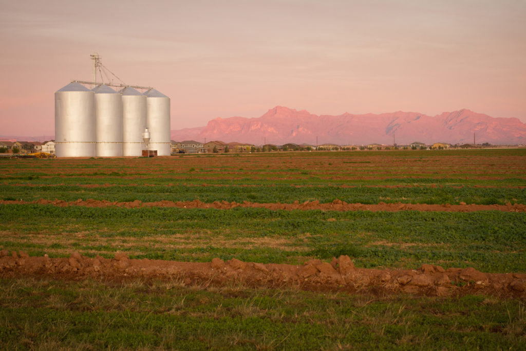 Silver grain elevators in Gilbert, Arizona, USA with pink setting sun