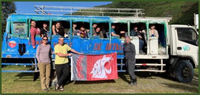 Several WSU students hold the Cougar flag beside a customized passenger "bus." 