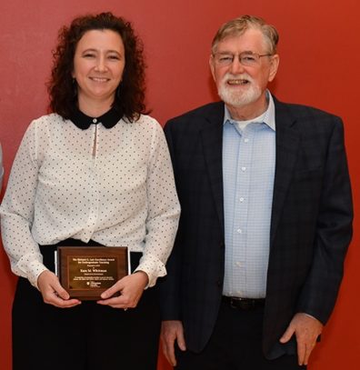Two people standing with award