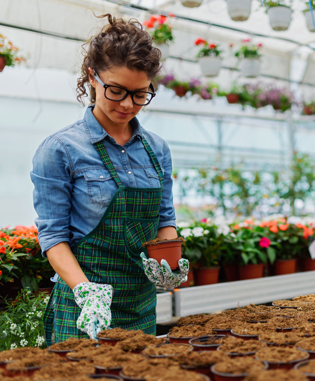 Young woman working in beautiful colorful flower garden greenhouse
