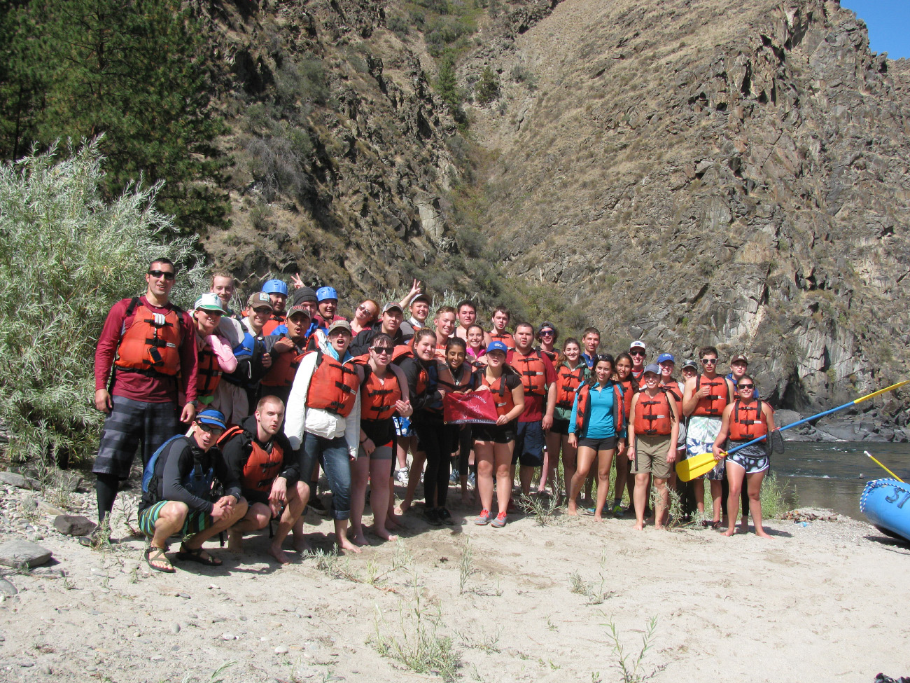Large group photo of SOE students at a river, wearing life jackets.