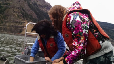 Geologists wearing life jackets conducting research on a boat.