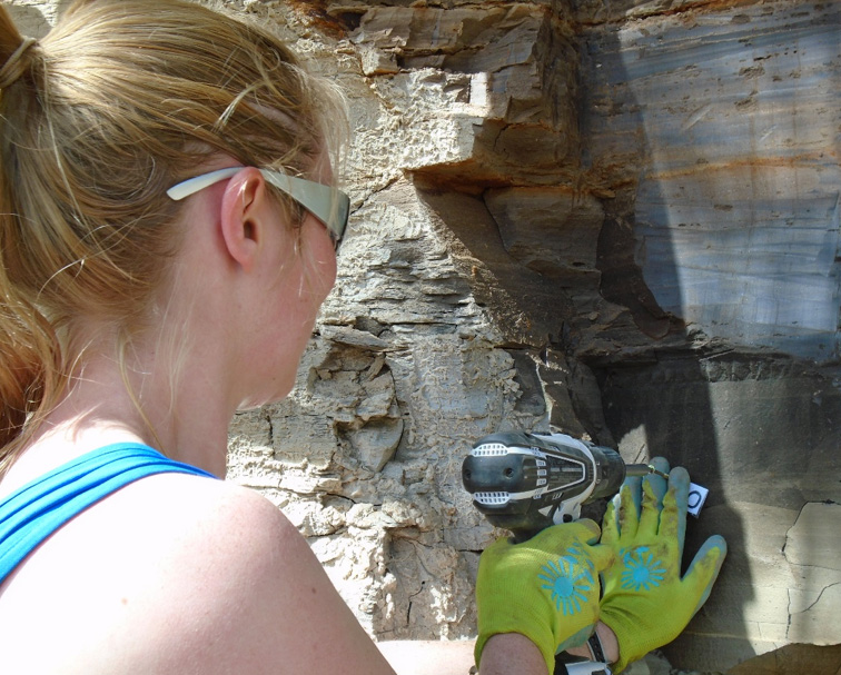 A geology student drilling into rock. 