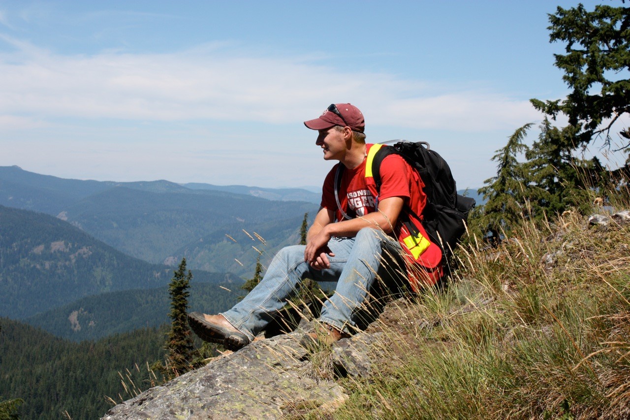A student sitting on a hillside enjoying the view.