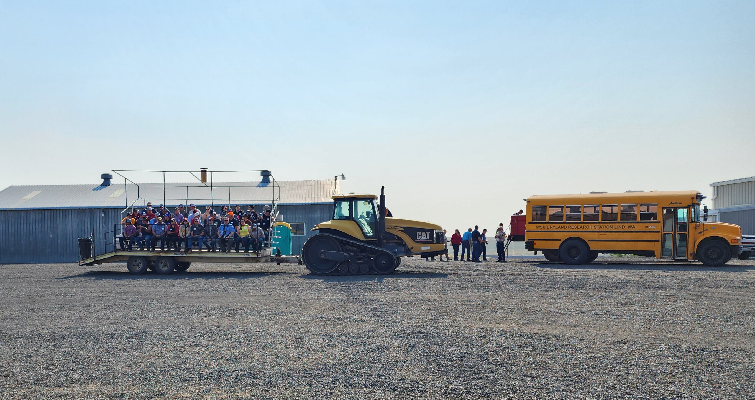 People in standings being pulled by a tractor.