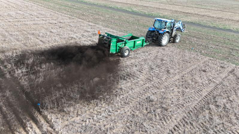 Tractor pulling a spreader disbursing biosolids.