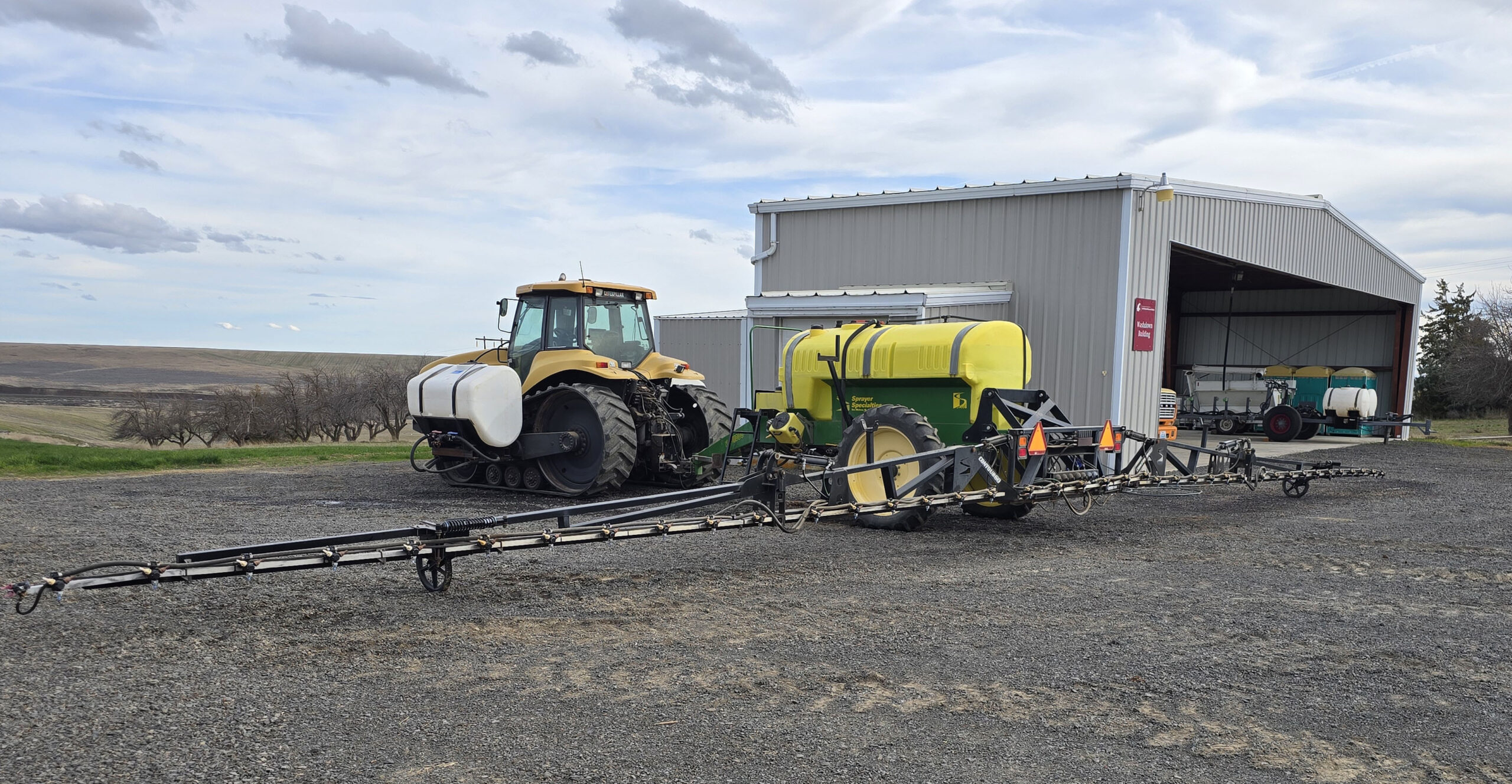 Tractor and sprayer next to a building.