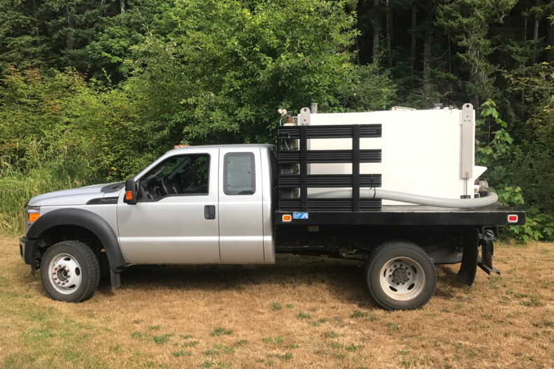Side-view of truck set up with tank to transport fish, on the flat bed.