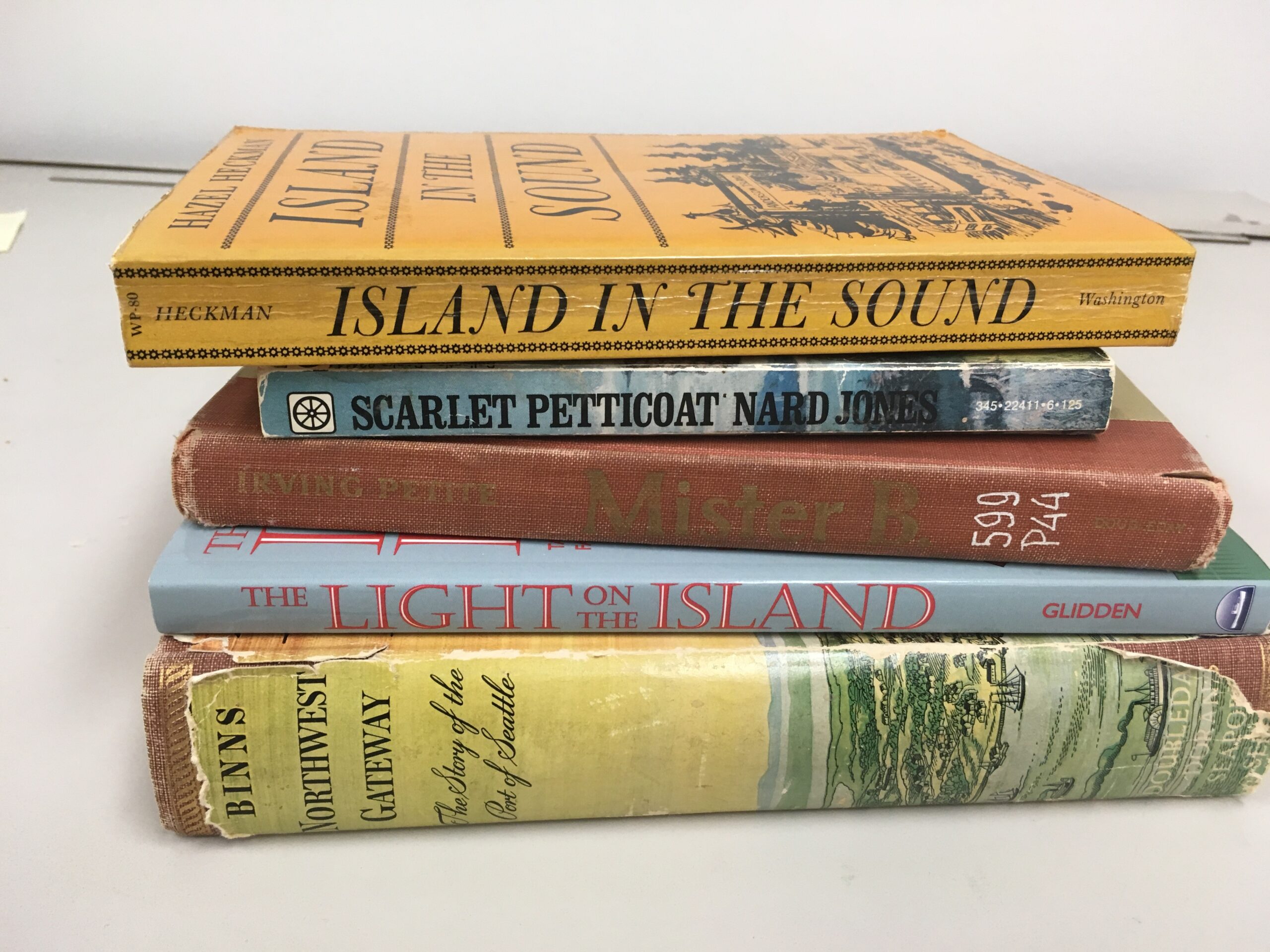 Stack of old books including Scarlet Petticoat by Nard Jones, Island in the Sound by Hazel Heckman, Mister B. by Irving Petite, The Light on the Island by Helene Glidden, and Northwest Gateway buy Archie Binns