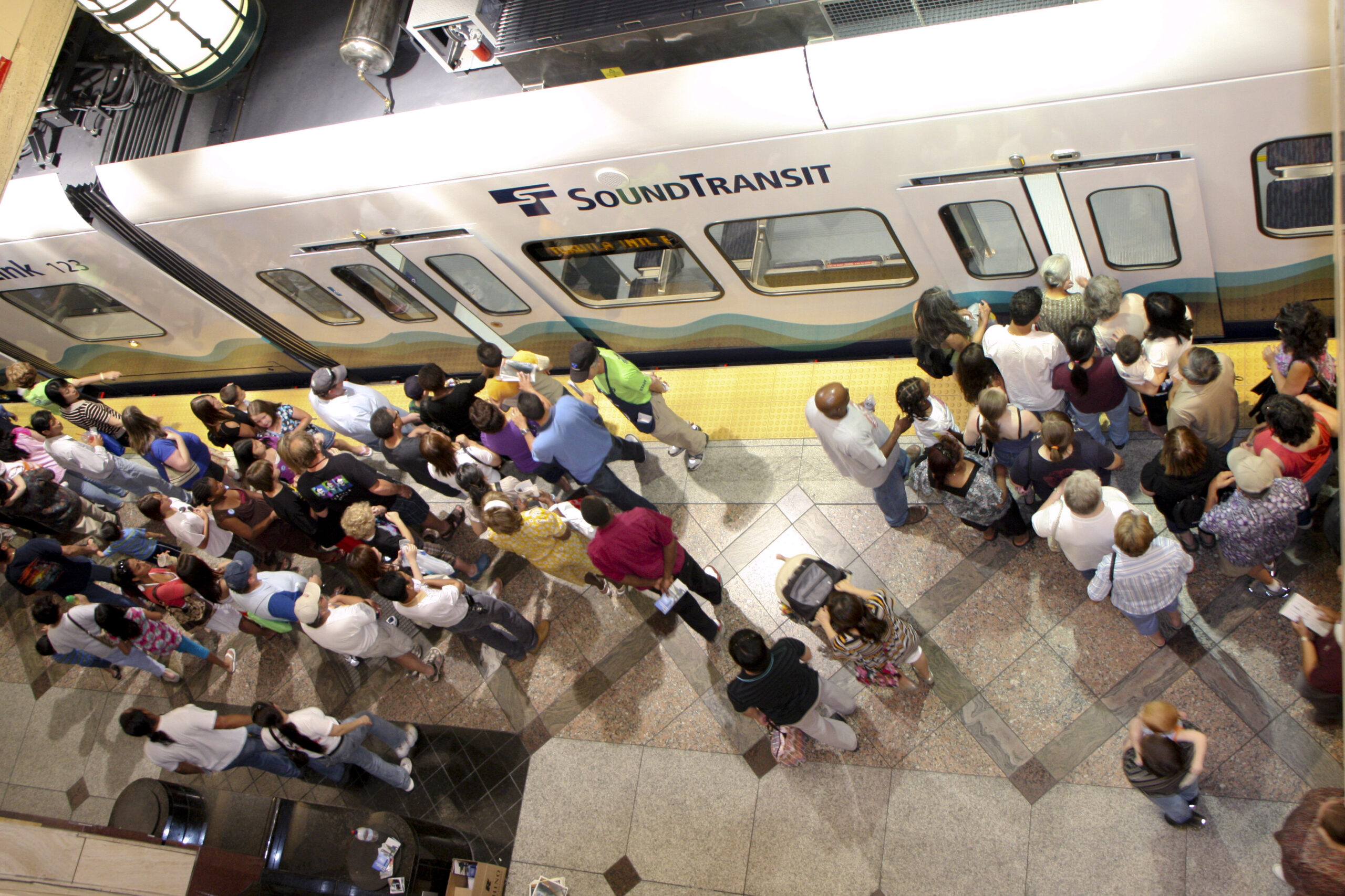 An oerhead view inside a Sound Transit station with people waiting to board the train