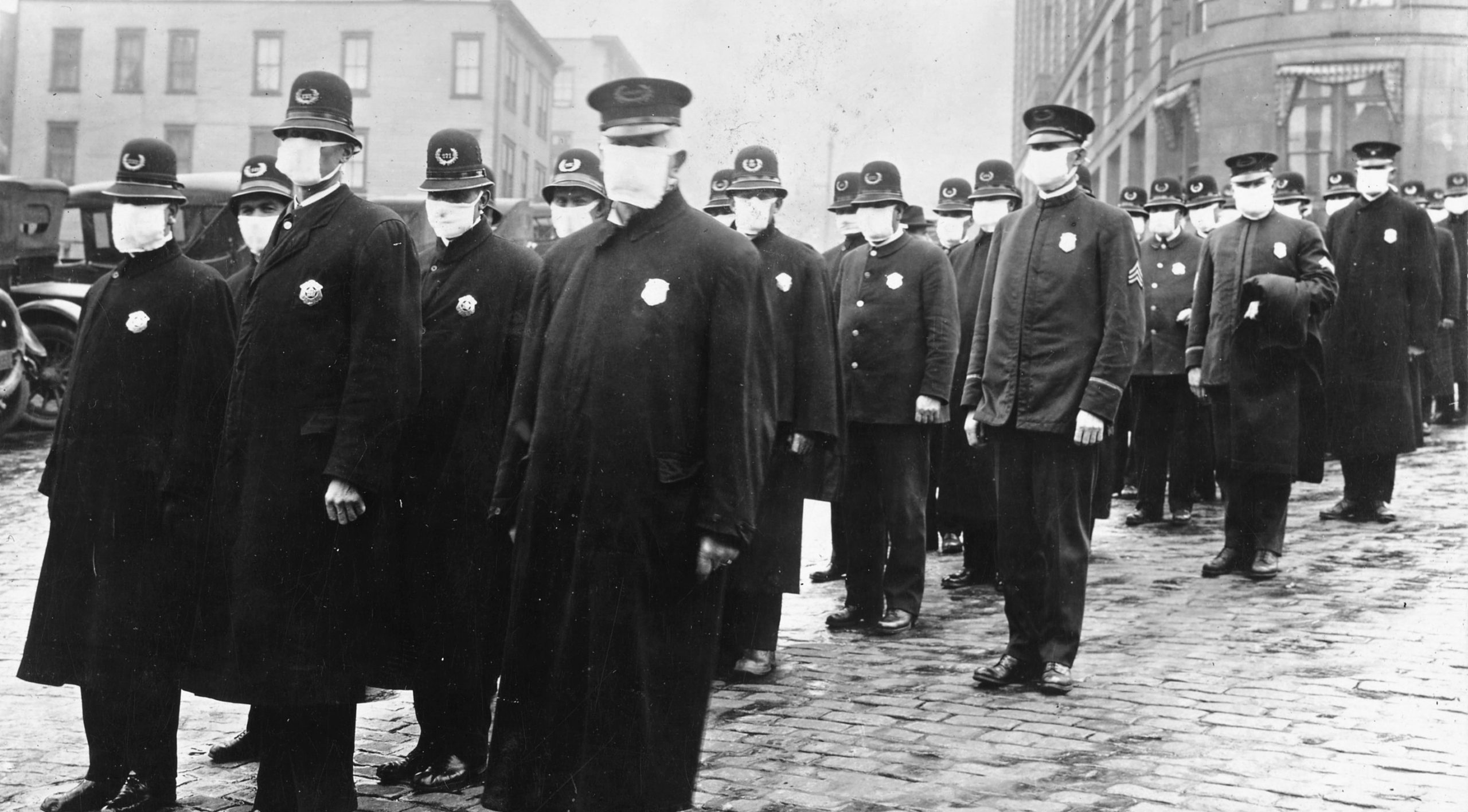 Uniformed policemen wearing gauze face masks stand in lines on a Seattle street.