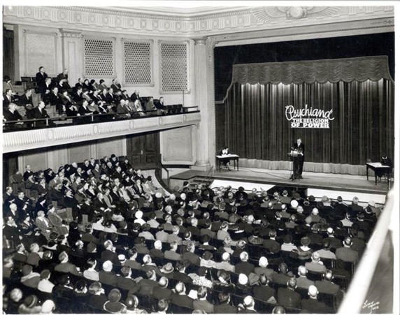 Psychiana leader Frank Robisnon on stage speaking before a large audience