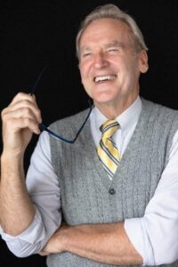 Recent photo of Mike Nolan, holding glasses and laughing.