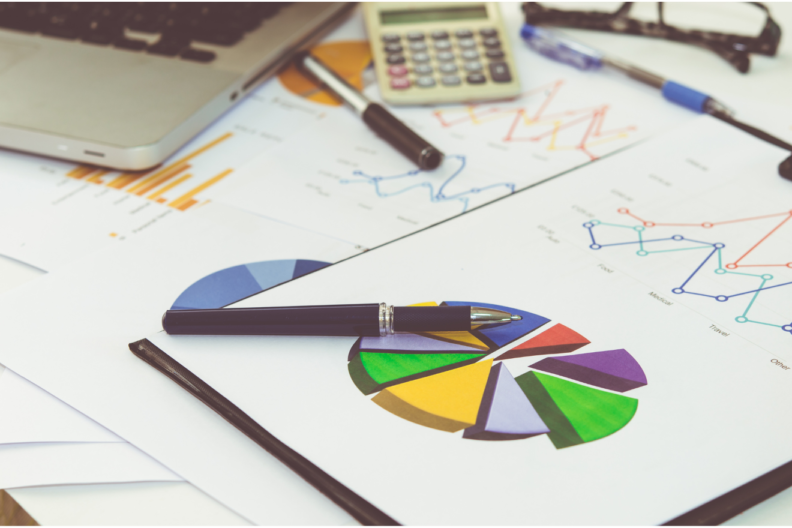 A closeup view of a clipboard with a colorful pie chart and other graphs representing data analysis.