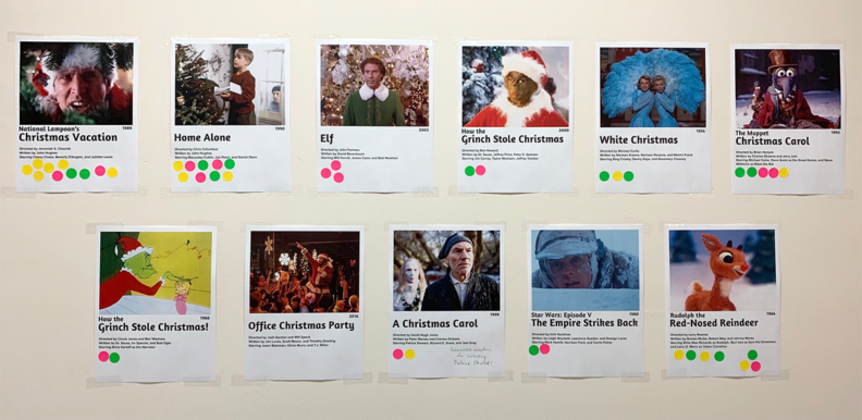 Collection of nominated holiday movies on the wall with dot-stickers for rank choice voting.