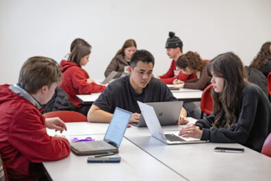 Students in a group studying on their laptops.